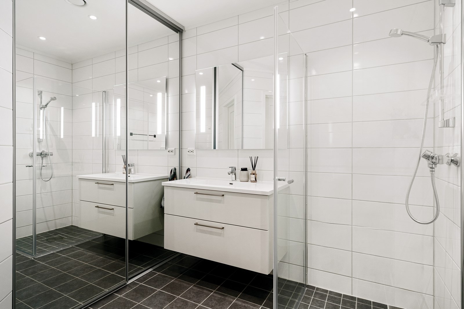 Badet er utstyrt med dusjvegger, vegghengt toalett og baderomsinnredning med heldekkende servant. Galleribilde