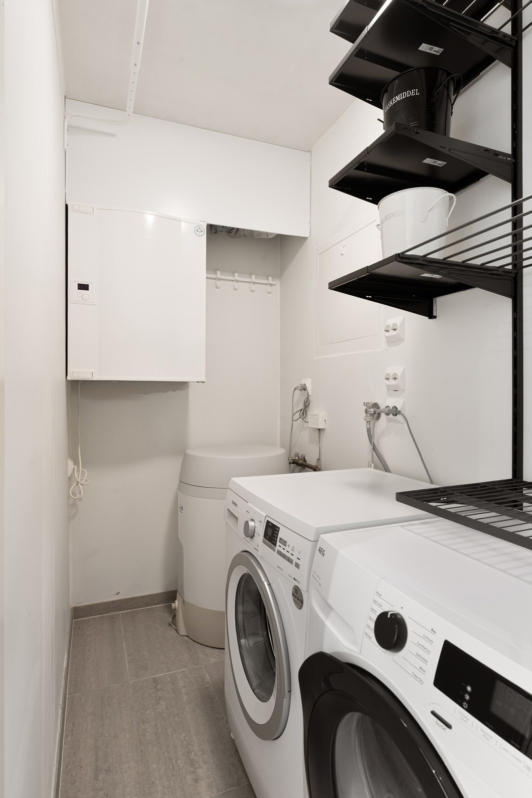 Innvendig bod med opplegg for vaskemaskin og tørketrommel, samt praktiske hylleløsninger. Galleribilde