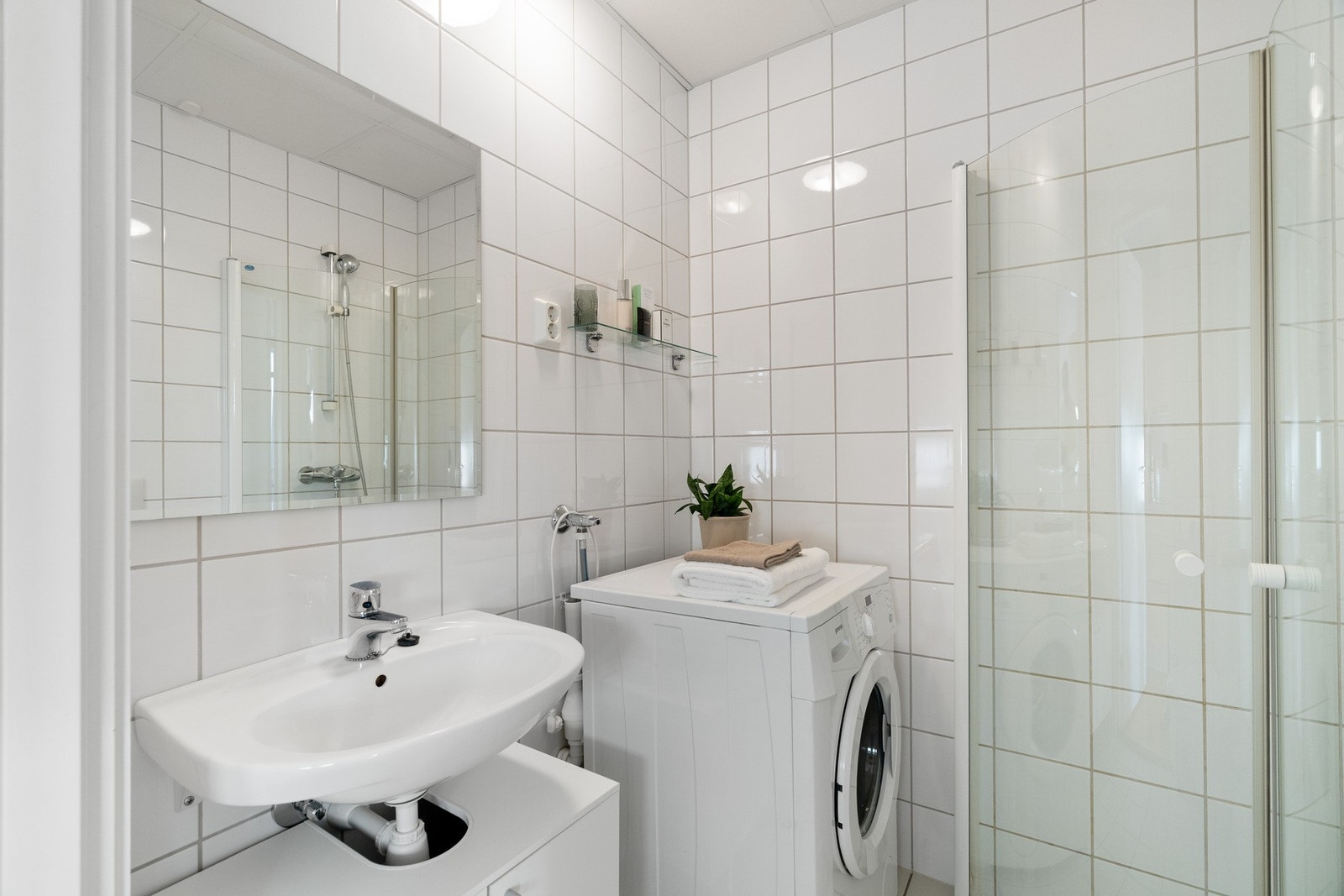 Utstyrt med servant, servantskap, speil, dusj med innfellbare dører, vegghengt wc, opplegg for vaskemaskin og varmekabler i gulv. Galleribilde