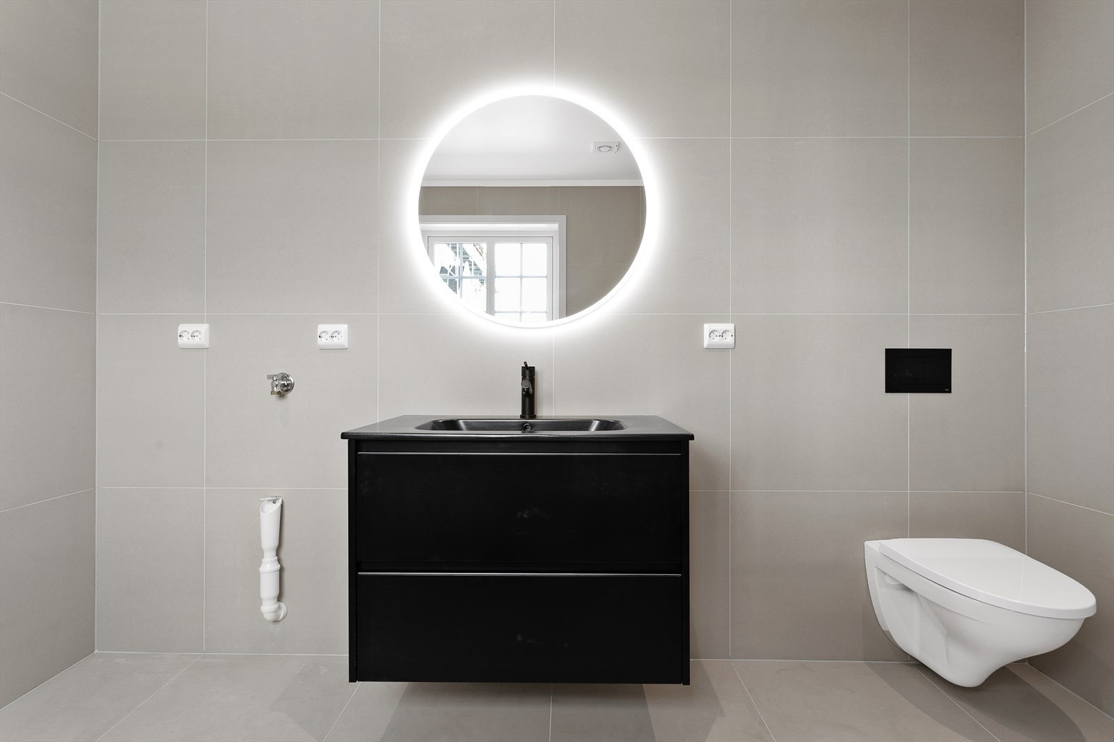 Badet fremstår som moderne og eksklusivt, og gir en god start på dagen. Her finner du store grå fliser på gulv og vegger, varmekabler og downlights som skaper en behagelig atmosfære. Galleribilde