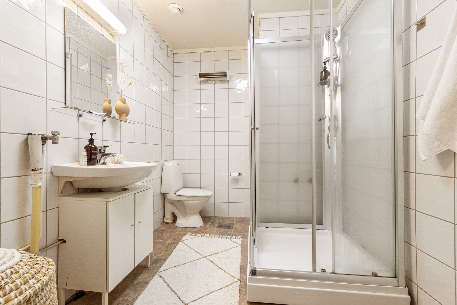 Eldre flislagt bad innredet med dusjkabinett, servant med underskap, toalett og opplegg for vaskemaskin, Galleribilde