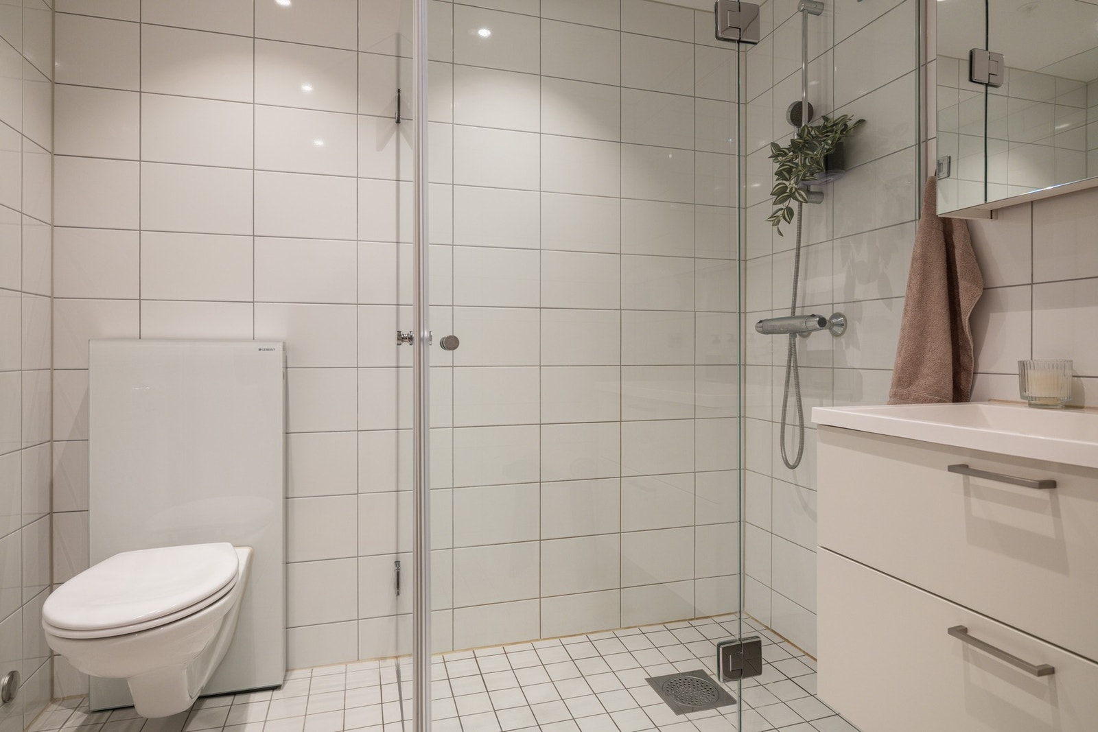 Badet har vegghengt toalett, samt dusjhjørne med innfellbare glassdører. Galleribilde