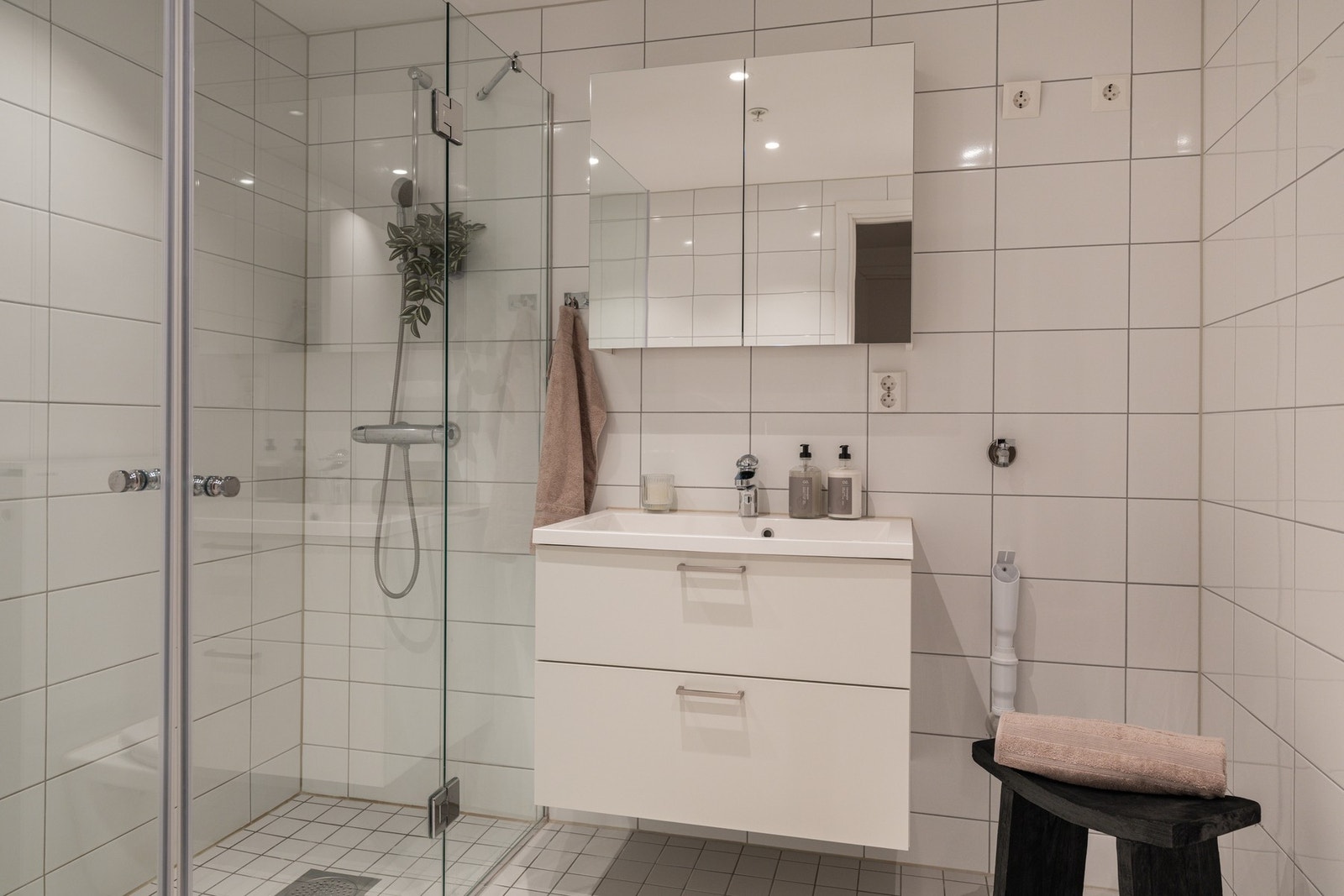 Delikat flislagt bad med moderne innredning, servant og speilskap. Galleribilde