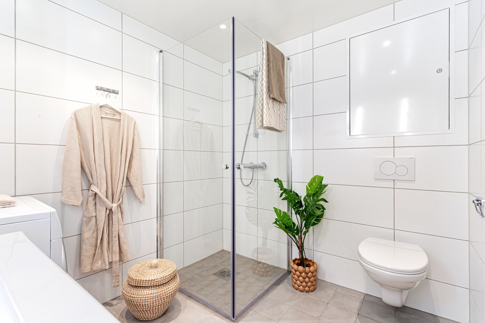 Et stilrent baderom som blant annet er innredet med toalett, dusj, servant med underskap og speil Galleribilde