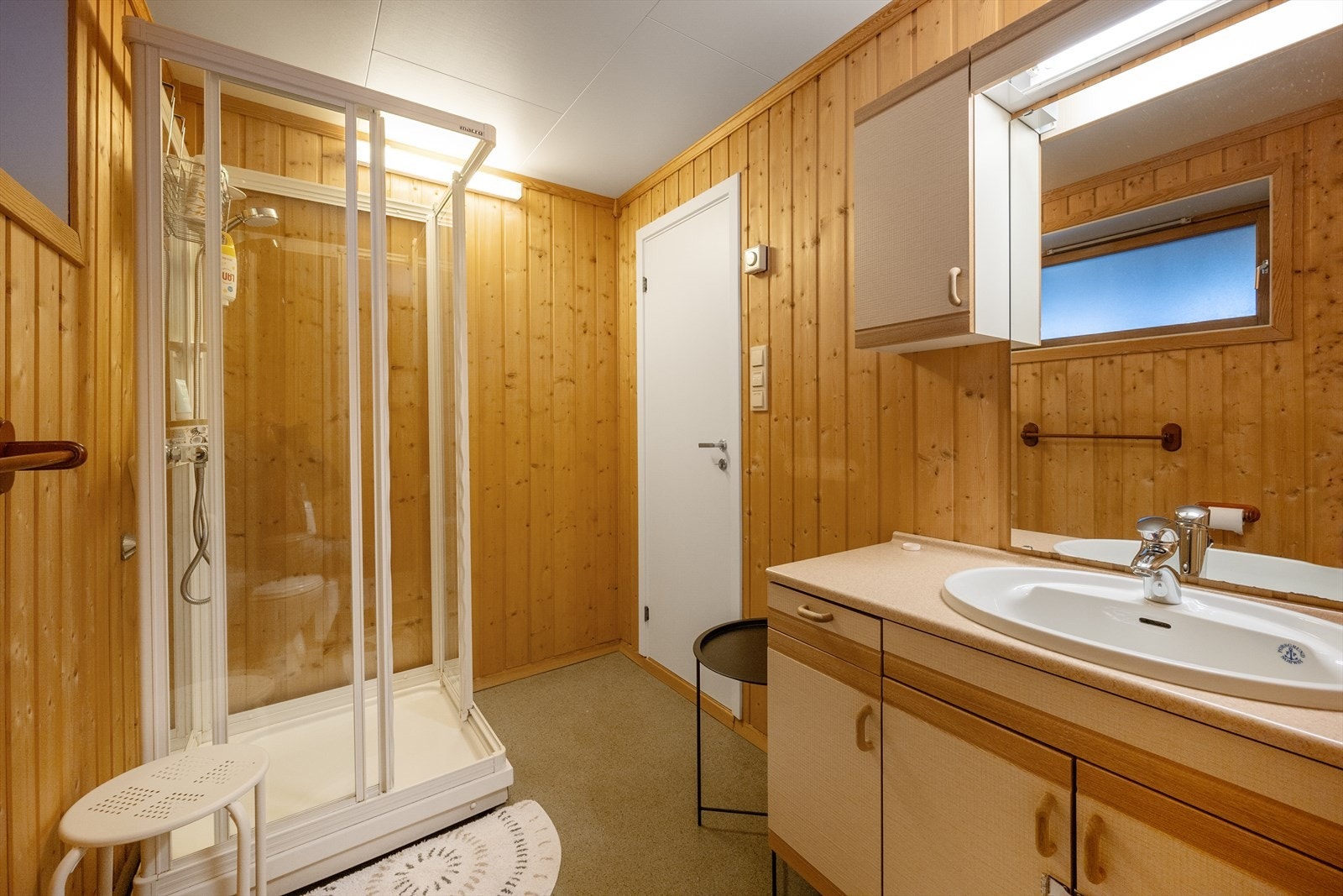 Baderommet er innredet med dusj, servant med underskap, speil og toalett. Galleribilde