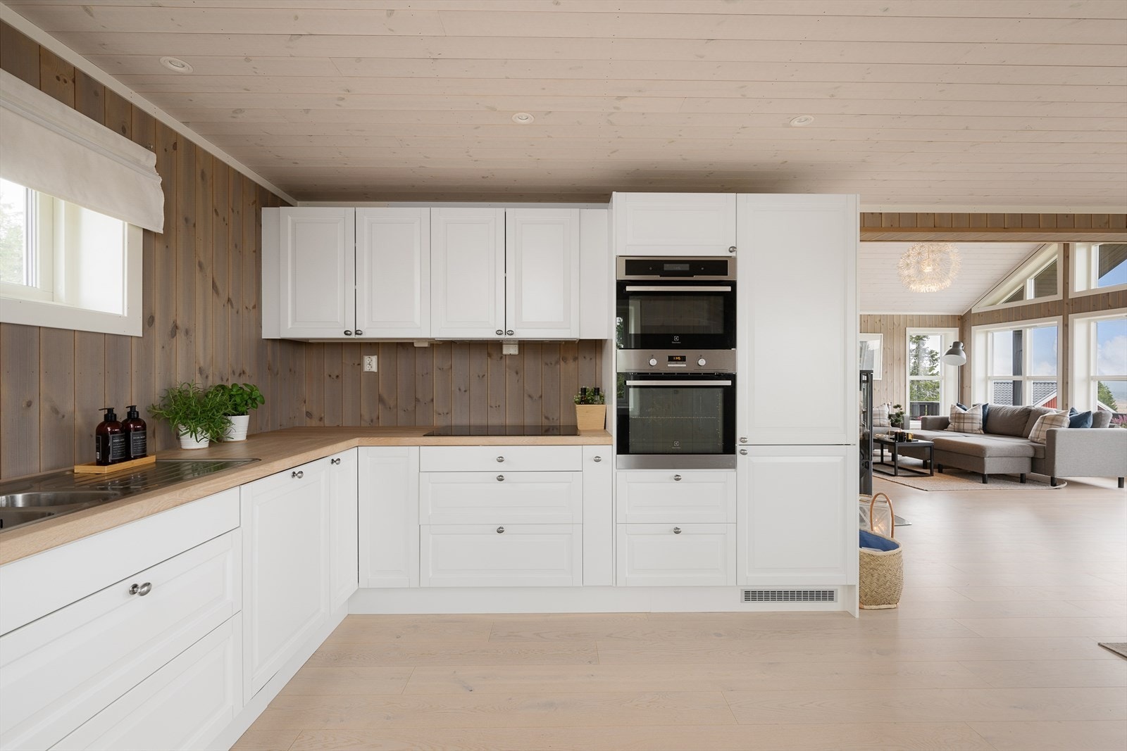 Det kommer godt med naturlig lys inn på kjøkkenet med vindu på to vegger. Den lyse innredningen står fint til de beisede panelveggene. Tidløst og innbydende. Galleribilde