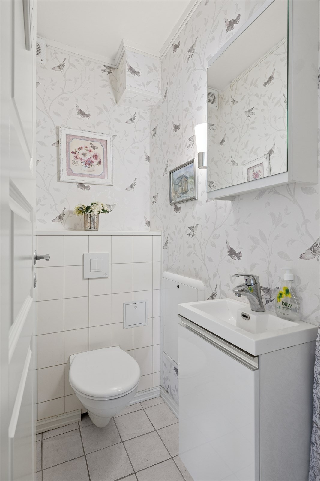 Separat toalettrom med flislagt gulv, tapet på vegger og malt betong i himling. Rommet er utstyrt med innebygget toalett og servant. Galleribilde