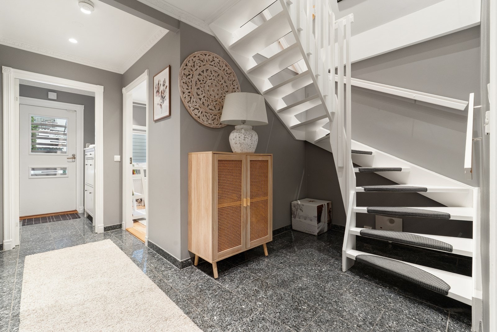 Velkommen inn i en romslig entré. Trappen i trekonstruksjon leder opp til første etasje. Galleribilde