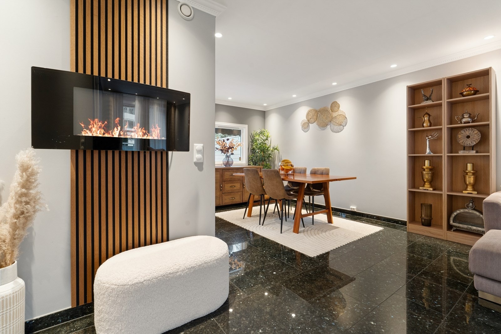 En dekorativ peis er montert på en vegg med spilepanel, som gir en lun atmosfære. Det er ikke tilkoblet pipe. Galleribilde