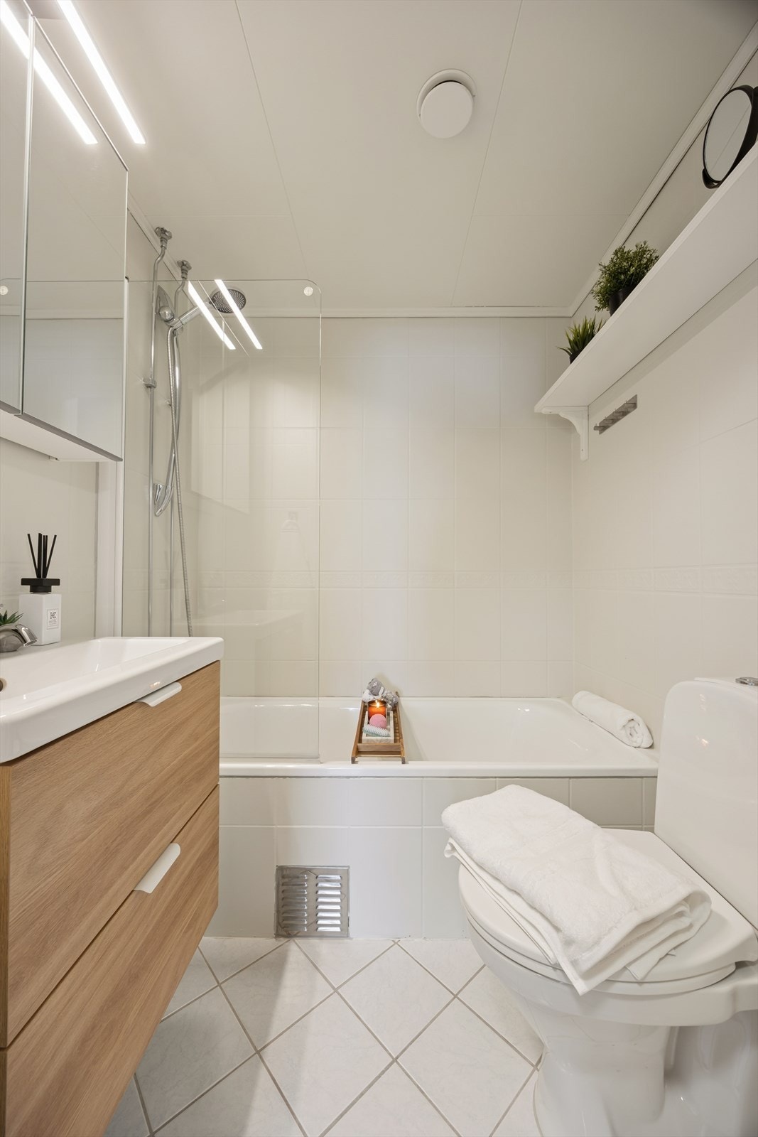 Badet er innredet med badekar med dusjløsning, toalett, nedfelt servant og tilhørende speilskap med belysning. Galleribilde