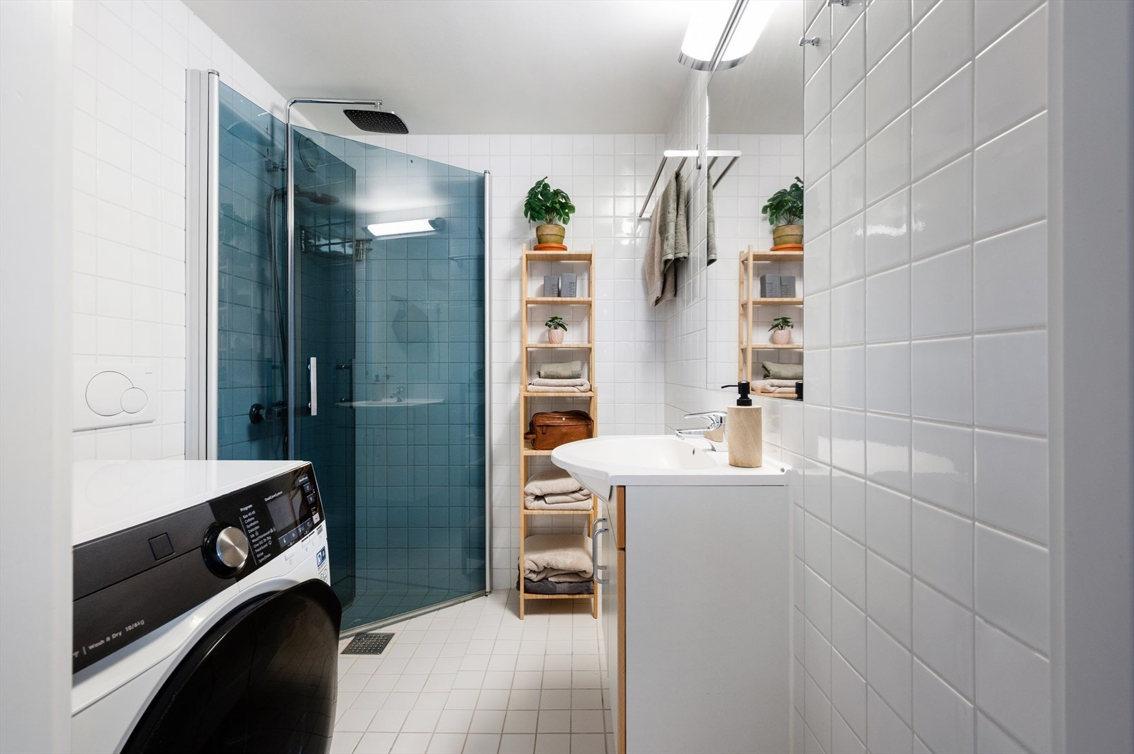 Pent og funksjonelt bad innredet med vegghengt toalett, servant nedfelt i innredning og dusjhjørne med svingbare glassdører. Galleribilde