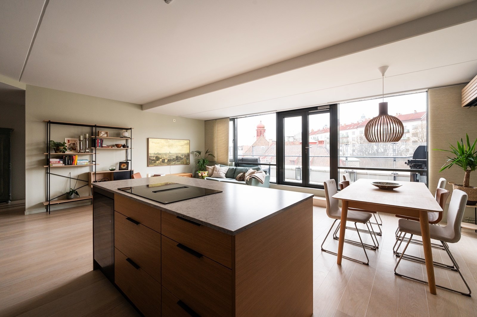 Den romslige kjøkkenøyen med steinplate og integrert induksjonstopp gir rikelig med arbeidsplass og inviterer til både matlaging og sosiale sammenkomster. Samtidig skaper kjøkkenøyen et naturlig og harmonisk skille mellom kjøkken- og stuesone. Galleribilde