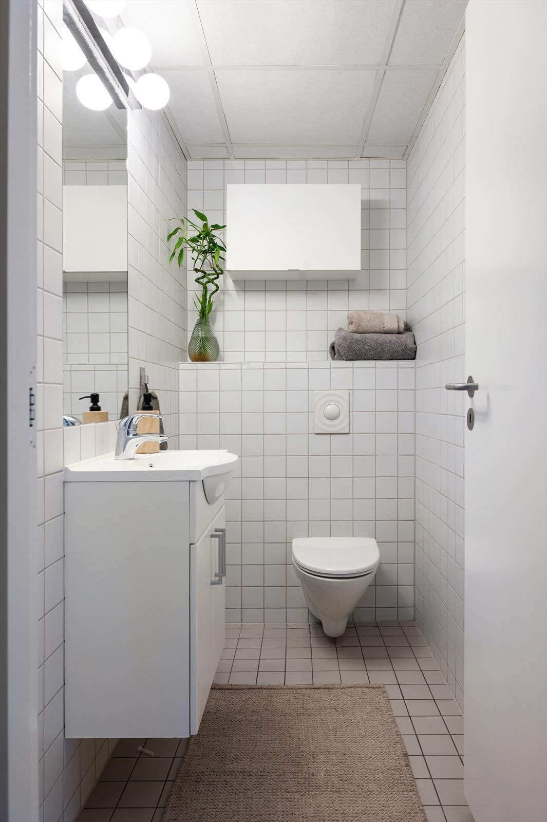 Innredet med vegghengt toalett, servant nedfelt i innredning og speil. Rommet ha videre flislagt gulv, flislagte vegger og malte himlingsplater. Galleribilde