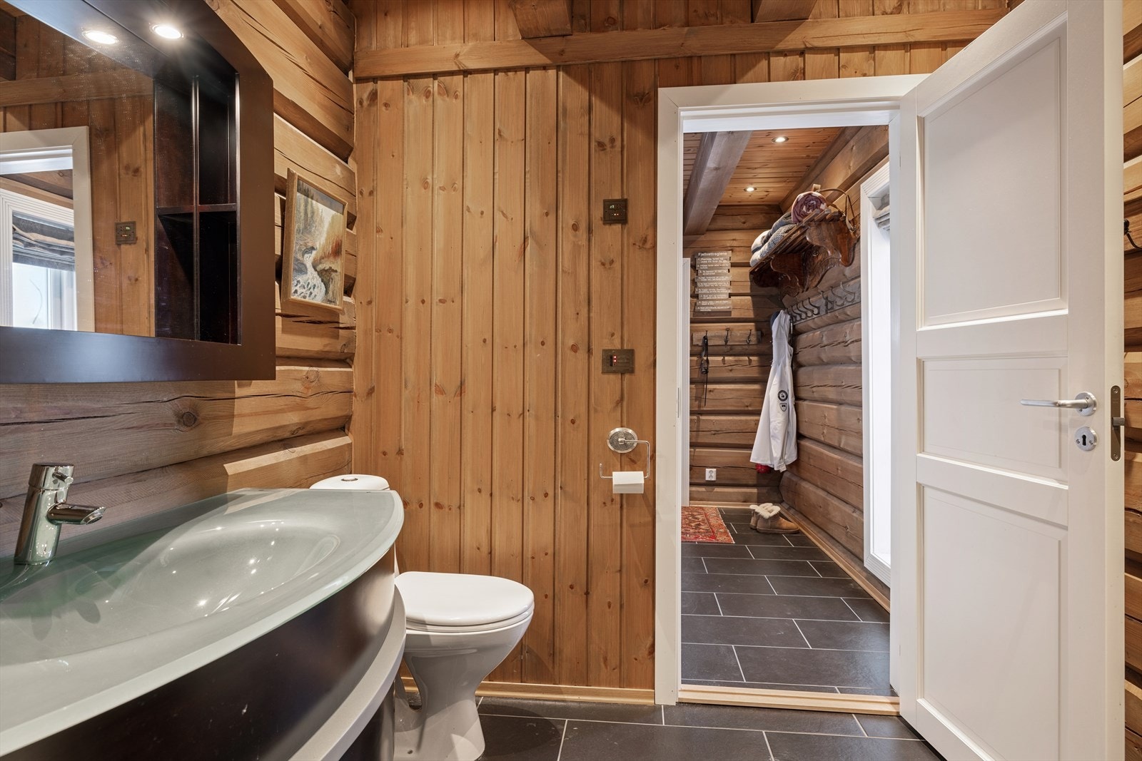 Badet er utstyrt med skapinnredning, sorte fronter med glatt finish, speil med integrert belysning og god oppbevaringsplass i skuffeseksjon Galleribilde