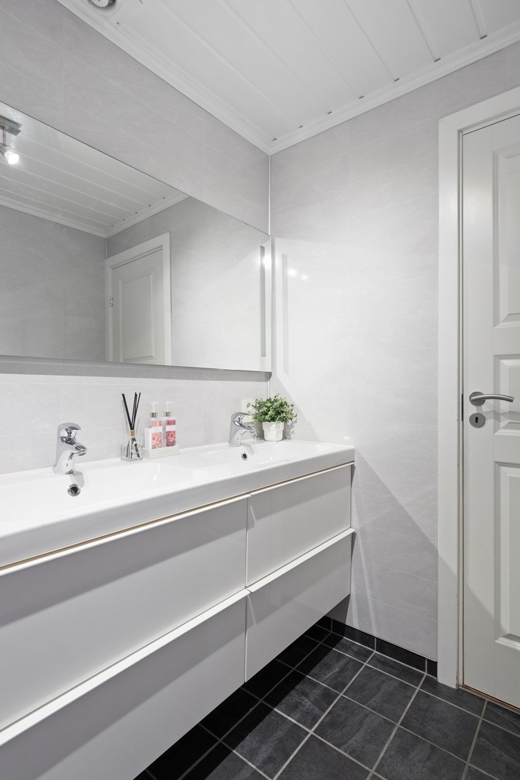 Nyere baderomsinnredning i hvit utførelse med dobbelservant med rom for oppbevaring i skuffeseksjon, speil og dusjkabinett. Galleribilde