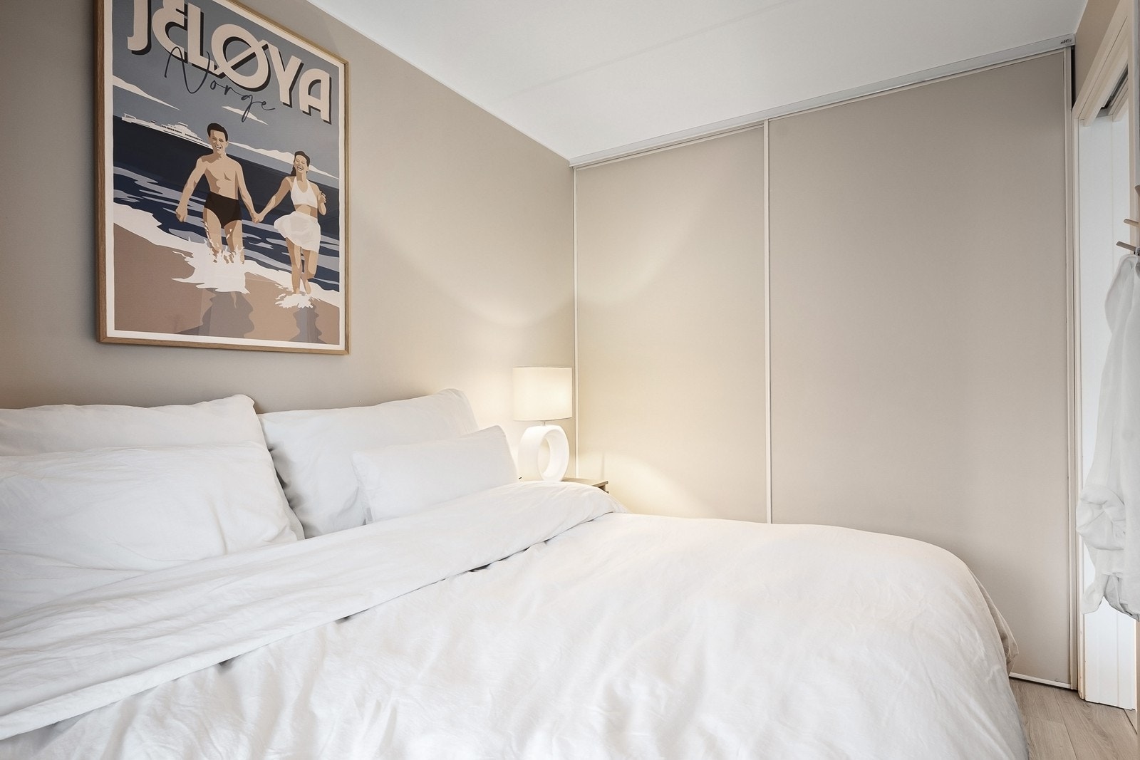 Stor skyvedørsgarderobe fra vegg til vegg. Vegger og garderobedører er malt i en behagelig fargetone og holder samme stil som resten av boligen Galleribilde