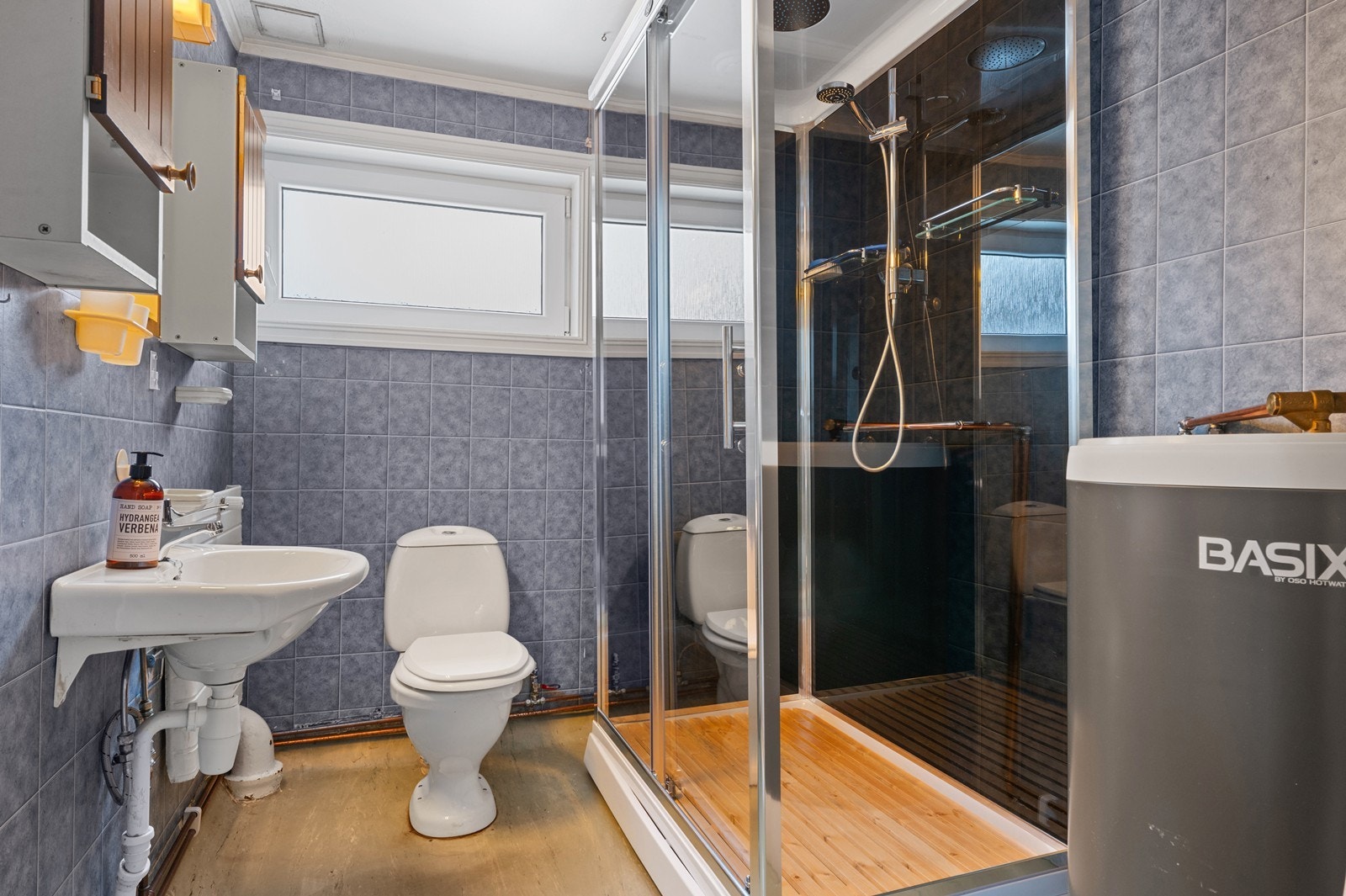 Etasjens bad er flislagt og innredet med dusjkabinett, servant og toalett. Galleribilde