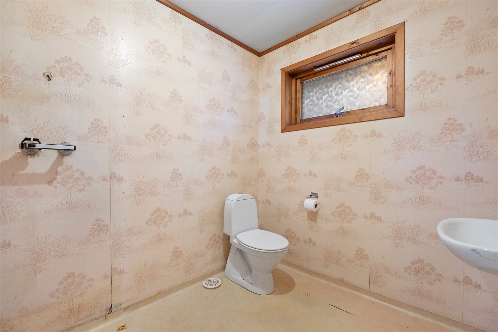 Badet har våtromsbelegg klemt i sluk og tapet på veggene, men det mangler dusjkabinett og dusjbatteri. Galleribilde