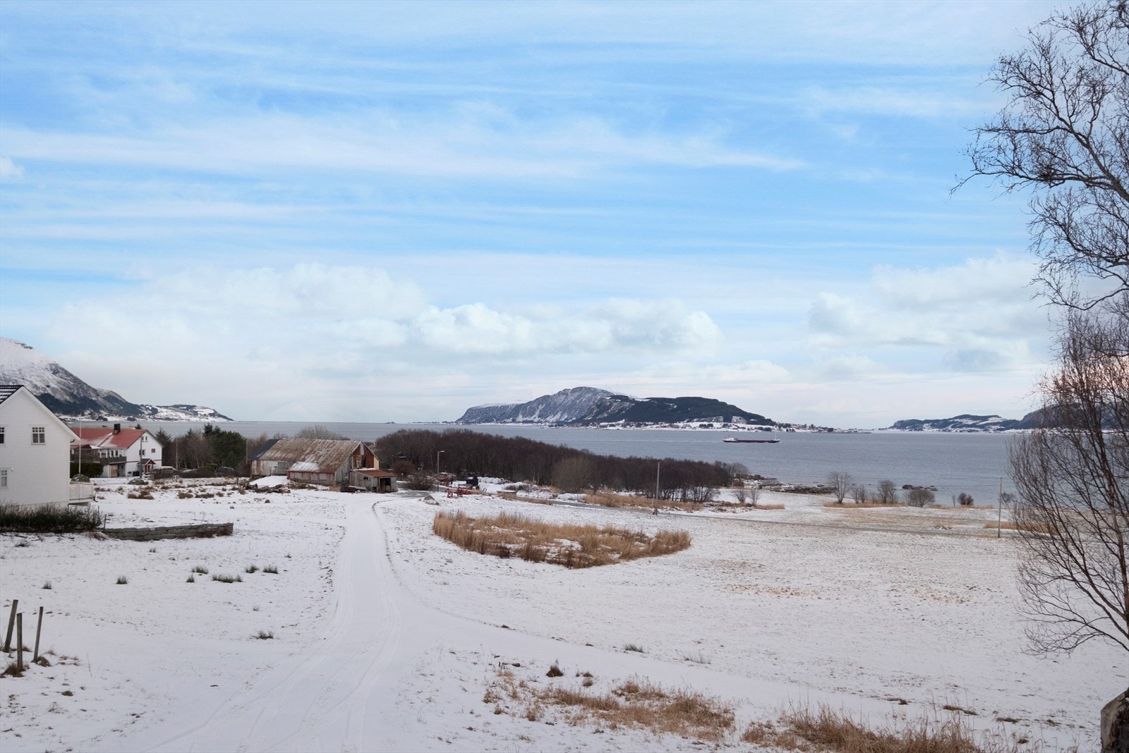 Utsikt fra eiendom mot fjorden, omgitt av snødekt landskap. Galleribilde