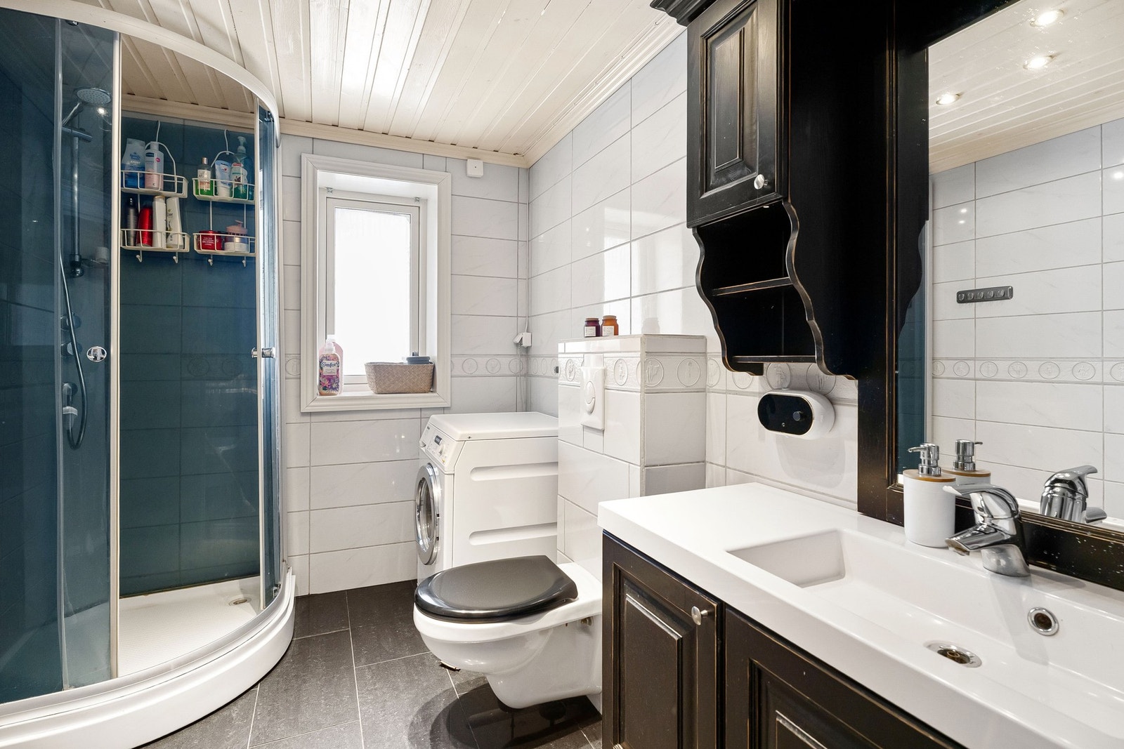 Baderom med dusjkabinett, vindu, vaskemaskin og servant med speil. Lys og moderne innredning. Galleribilde