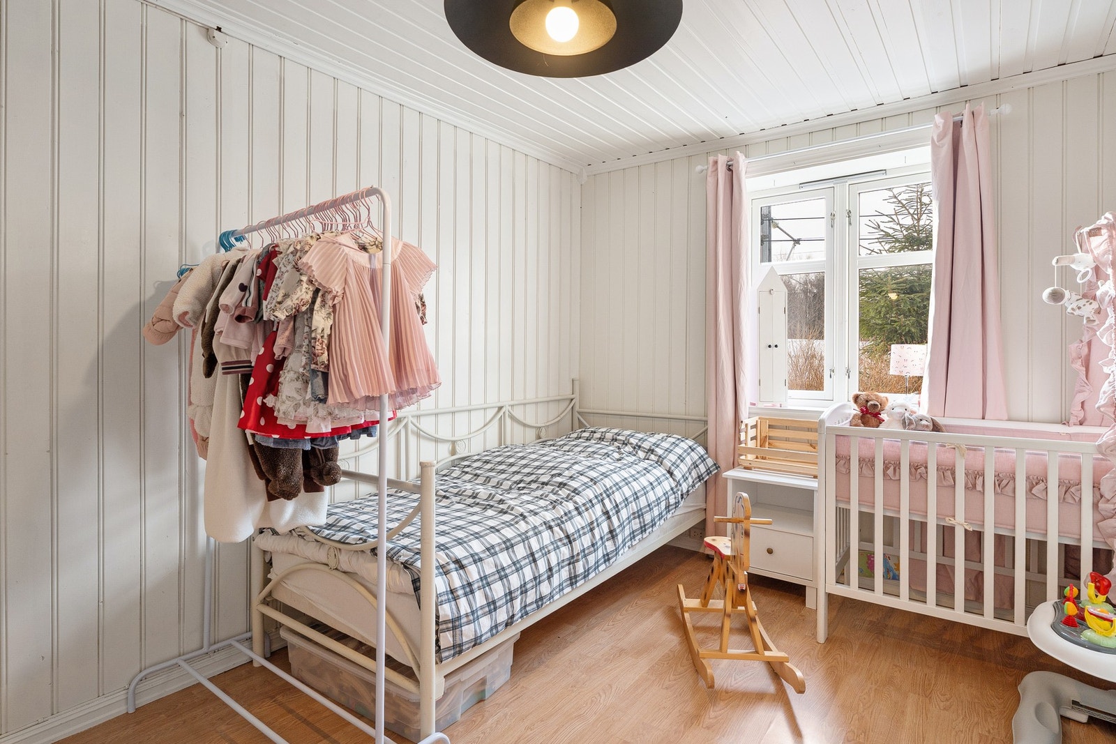 Lyst barnerom med panelvegger og vindu som gir godt med naturlig lys. Galleribilde