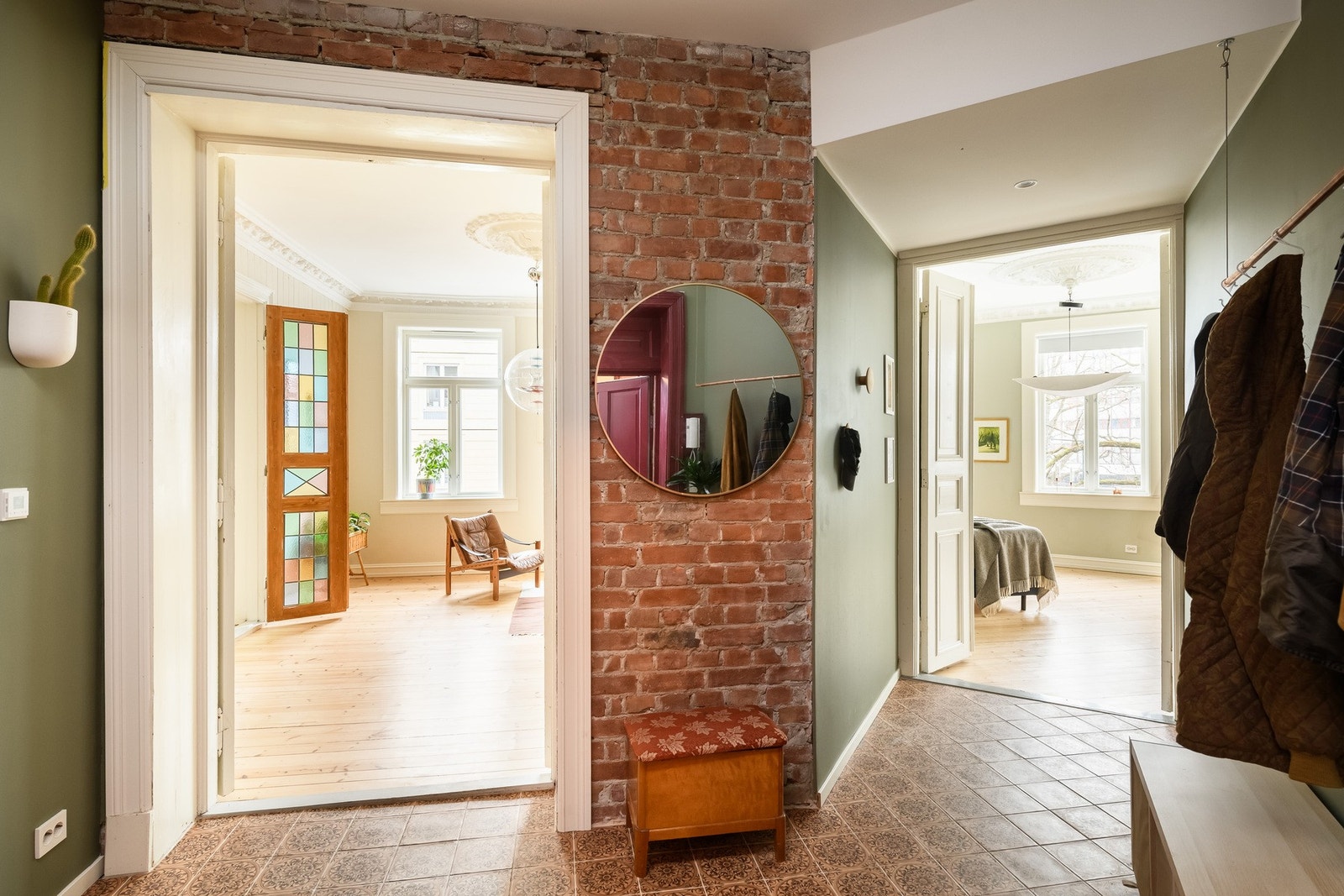 Entréen har flislagt gulv med varmekabler og en karakterfull vegg med synlig teglstein. Galleribilde