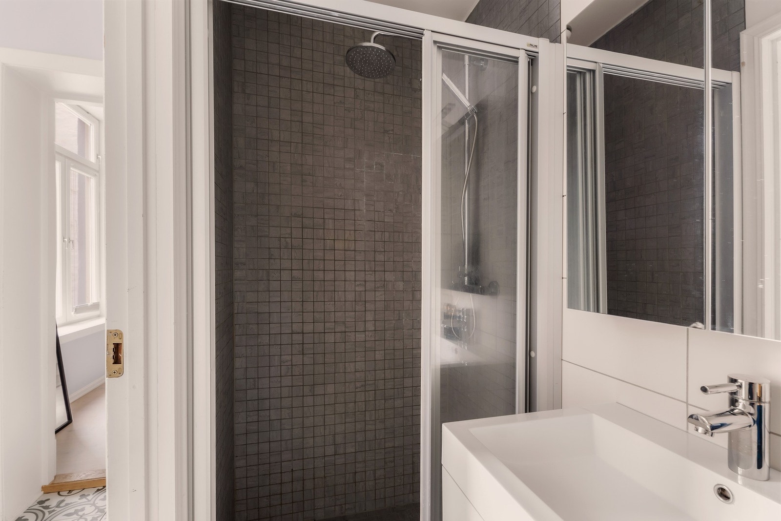 Rommet er flislagt med gulvvarme i gulv og flislagte vegger, som gir et tidløst og lettstelt uttrykk Galleribilde