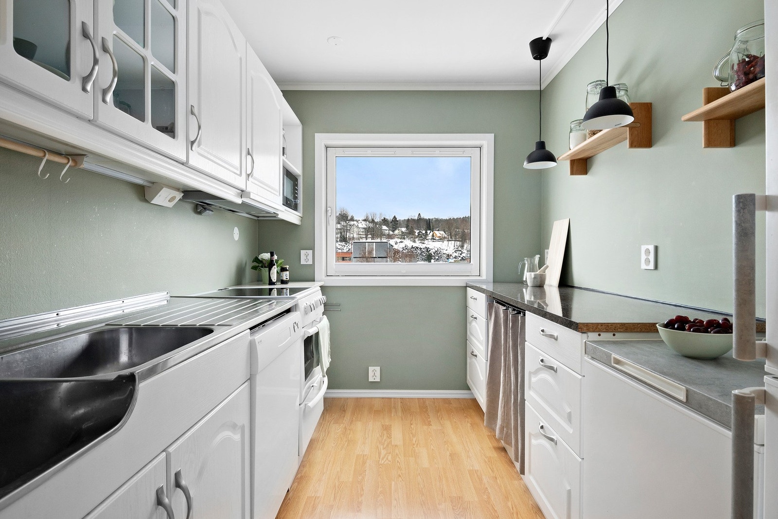 De hvite, profilerte frontene gir et lunt og klassisk uttrykk, mens den mørke benkeplaten tilfører kontrast og karakter. Galleribilde