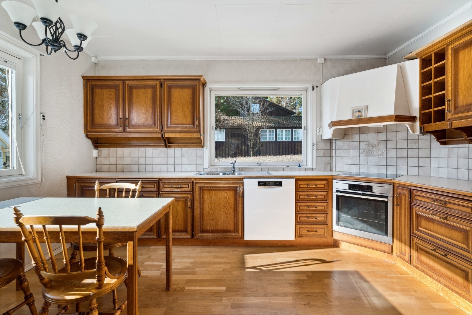 Romslig kjøkken med bord og hvitevarer - Kjøkkenet er nå malt i en grå farge. Galleribilde