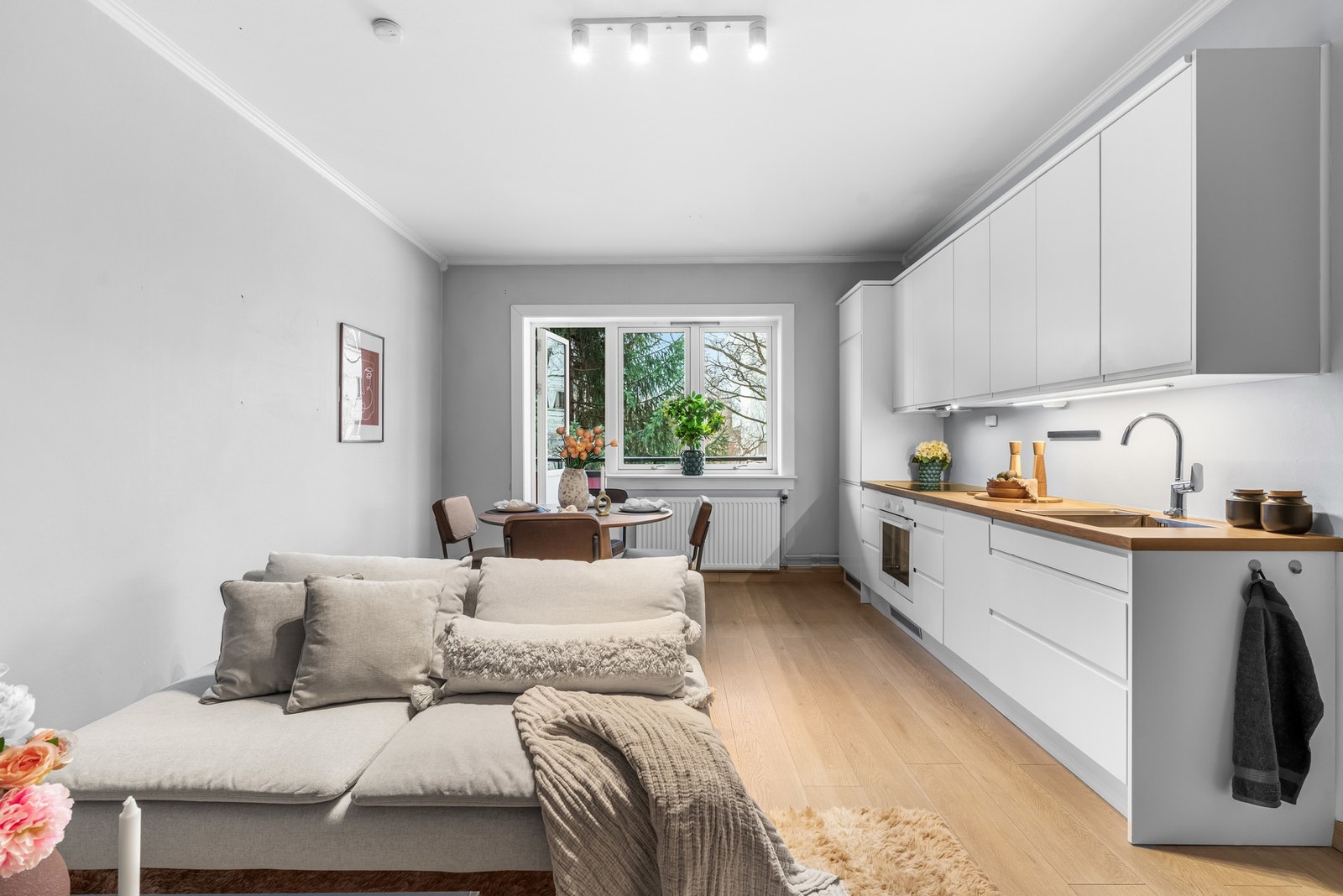 Åpen stue- og kjøkkenløsning med naturlig lys som blir sluppet inn via vinduene og balkongdøren. Galleribilde