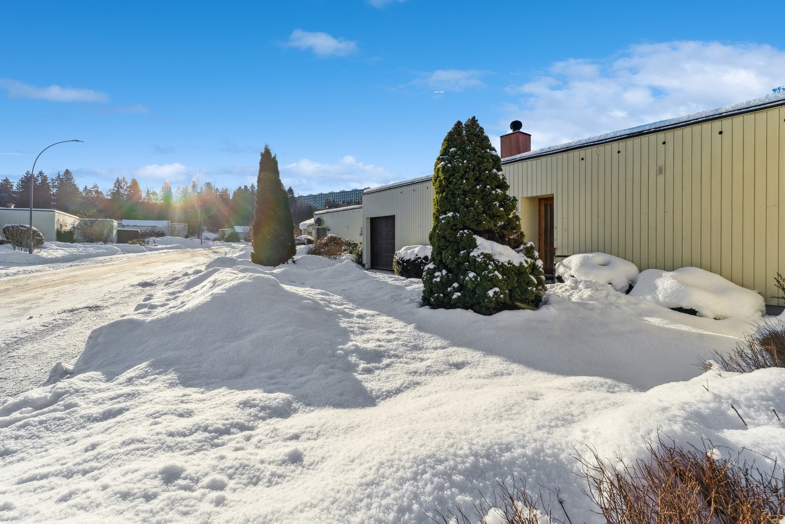 Fasaden fra inngangspartiet med garasje og naturlig biloppstillingsplass foran garasjen. Elektrisk garasjeport. Galleribilde