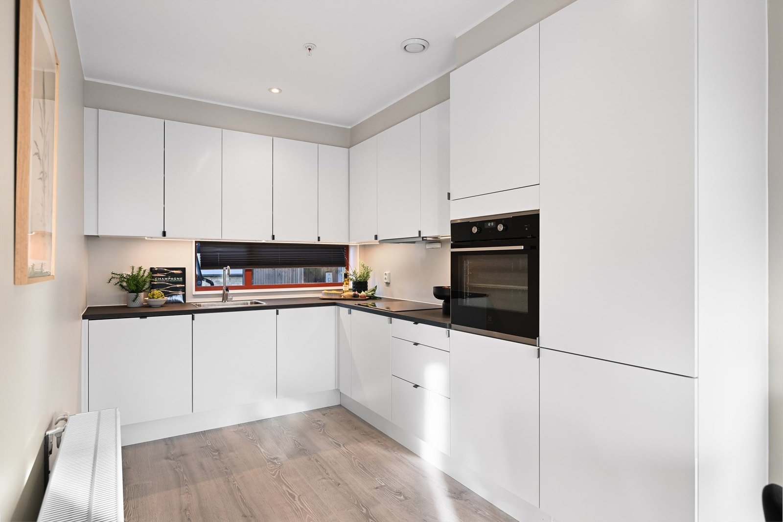 Innredninger er fra byggeår med glatte hvite fronter og svart benkeplate i laminat Galleribilde