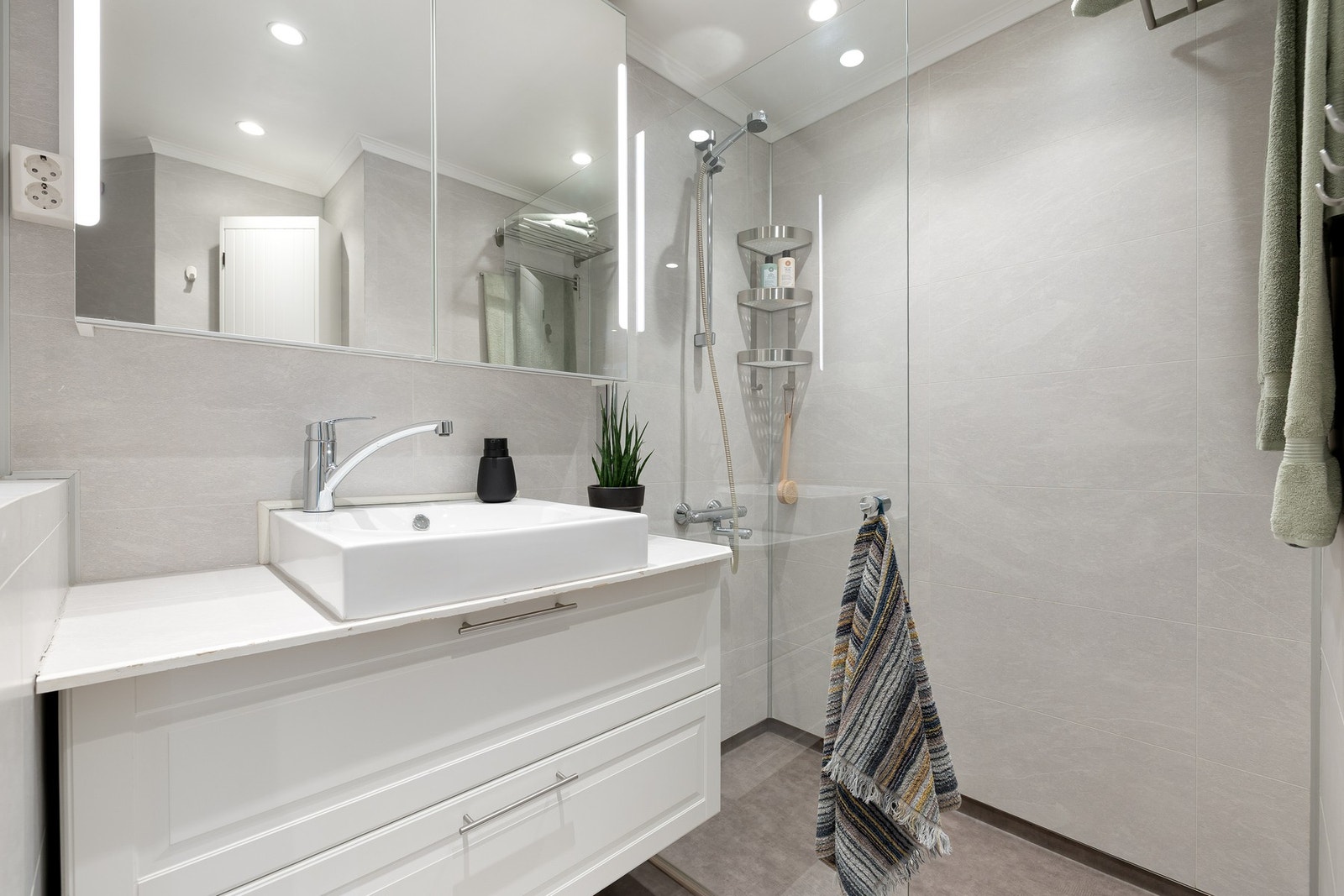 Badet er innredet med dusjhjørne med innfellbar glassdør og veggmontert toalett. Galleribilde