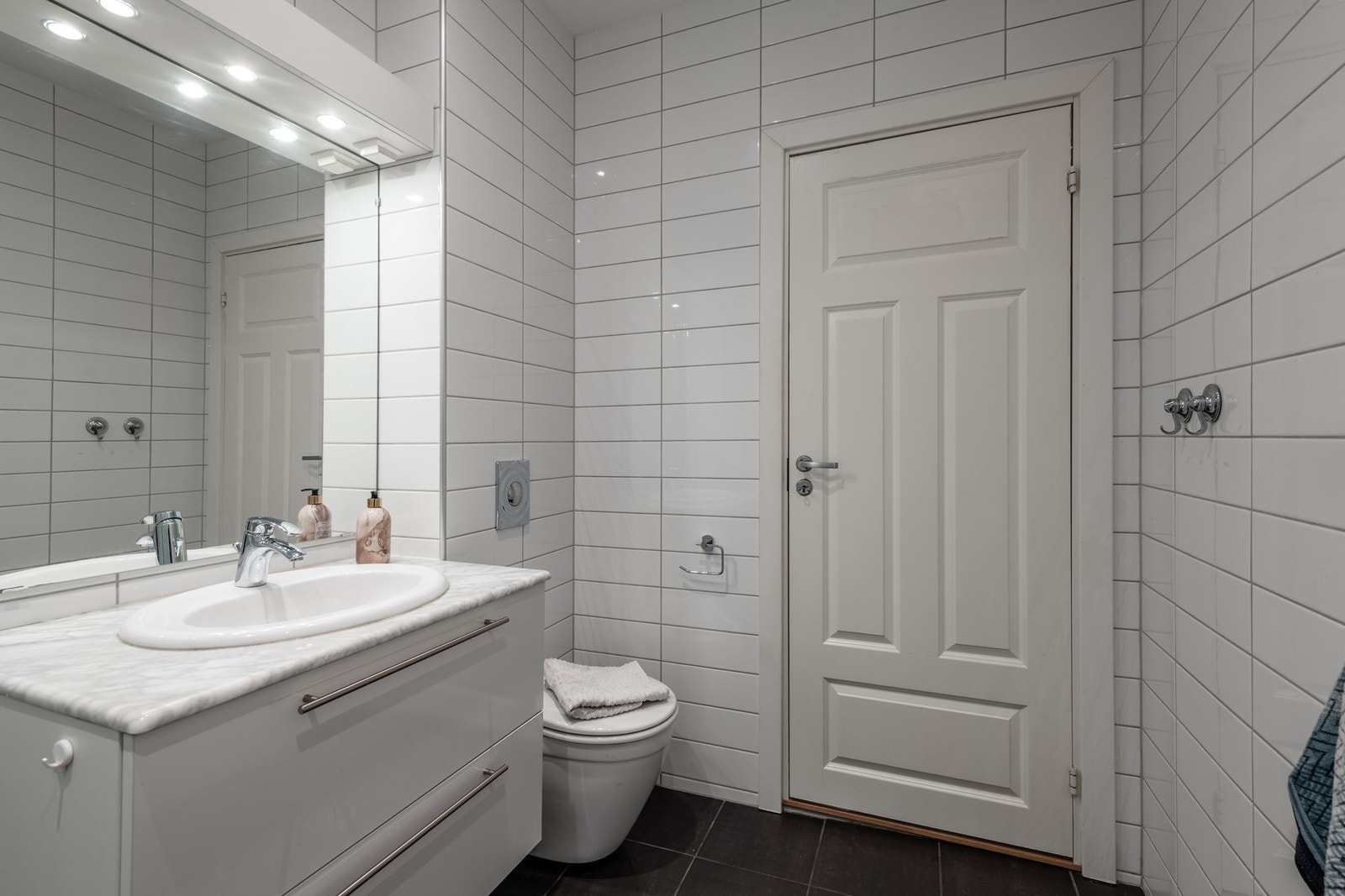 Badet har servantinnredning, håndvask, veggtoalett og dusj med dører i glass Galleribilde