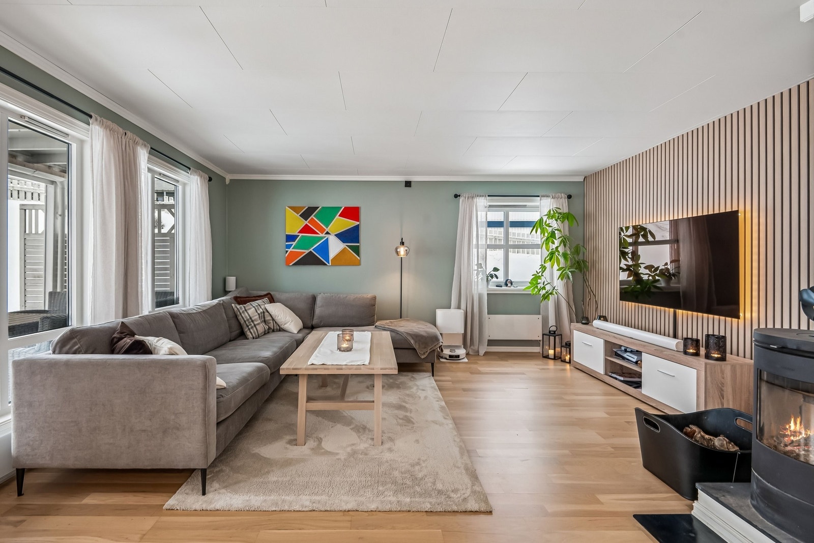 Romslig og lun stue med pen spilevegg, og peisovn Galleribilde