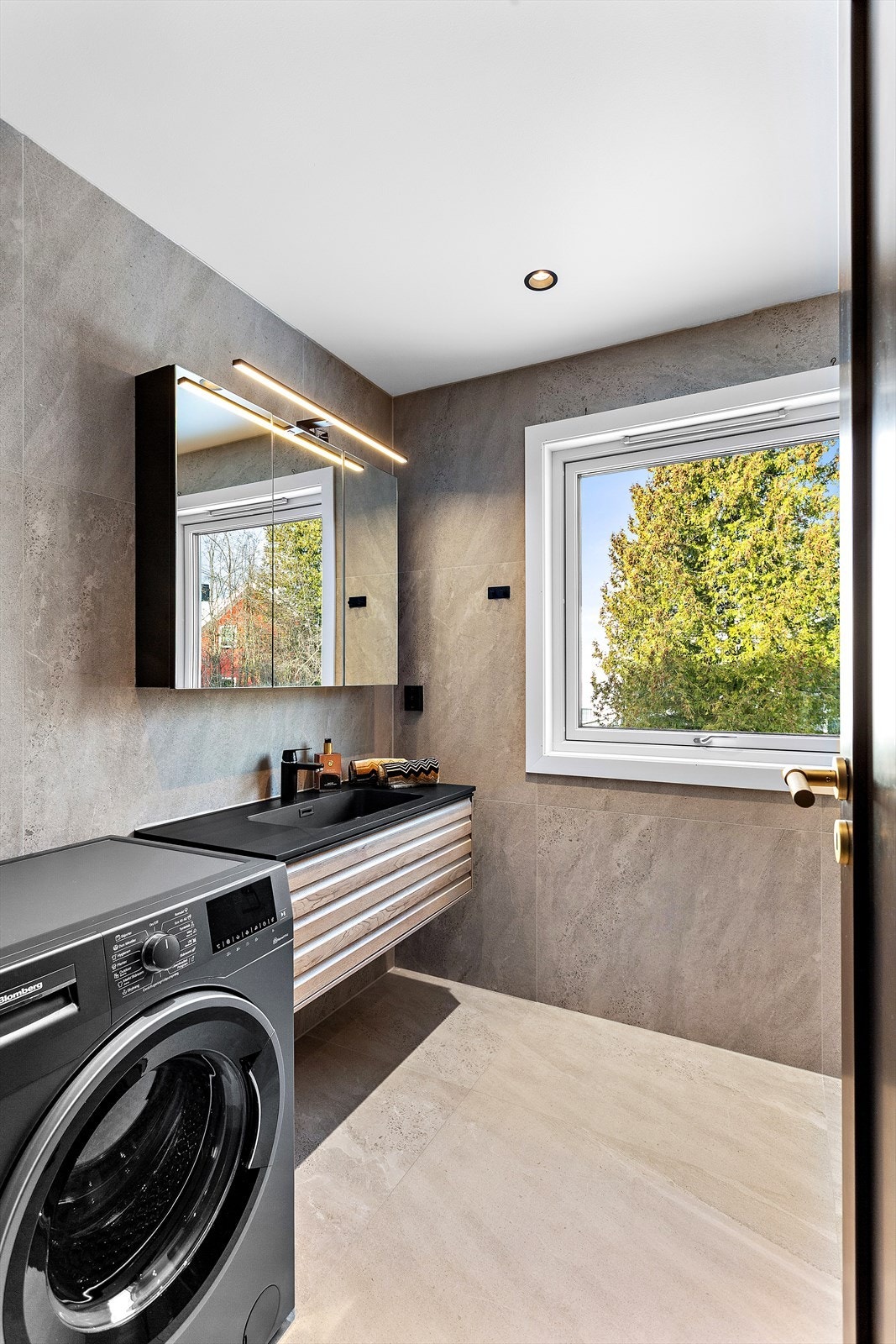 Badet har en stilren innredning og praktisk opplegg for vaskemaskin. Galleribilde