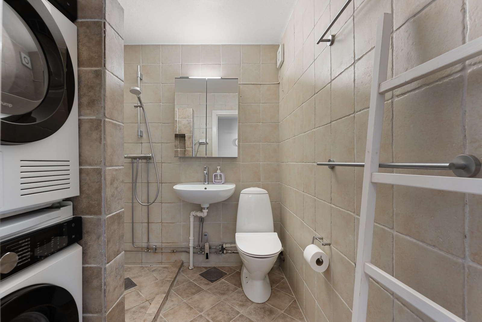 Flislagt bad med dusjhjørne og praktisk opplegg for vaskesøyle. Galleribilde