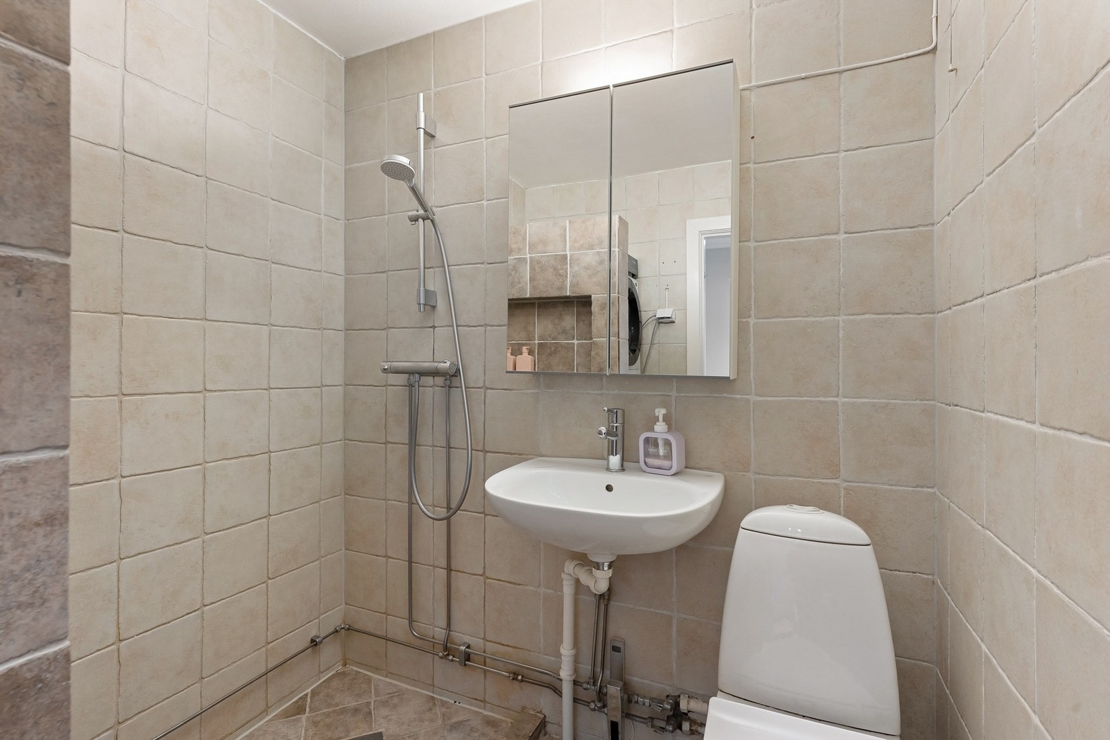 Badet er utstyrt med servant, speilskap med belysning og toalett. Galleribilde