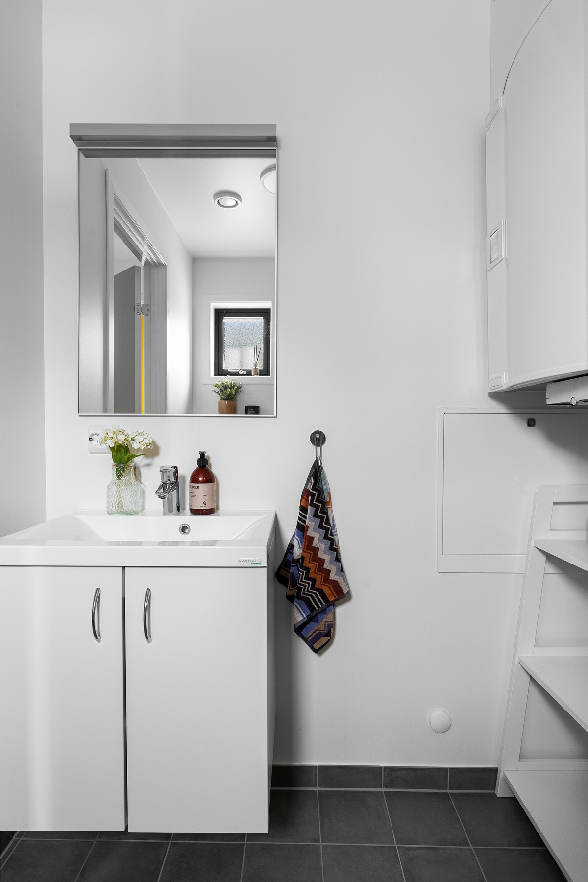 Wc/vaskerommet i boligens første etasje har fliser på gulv og malte veggflater. Rommet er innredet med servantskap og speil. Galleribilde