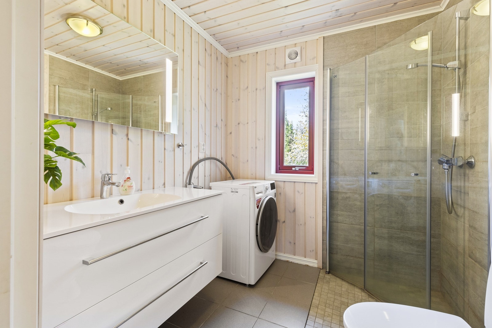 Bad med dusjhjørne som har foldedører av glass og vaskemaskin Galleribilde