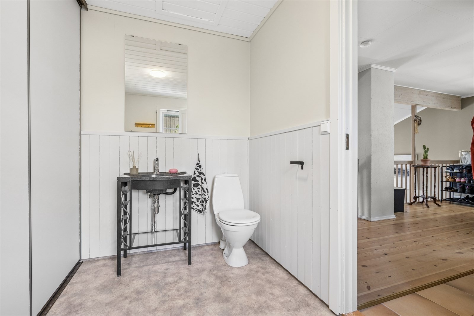 Toalettrom med adkomst fra boligens gang som er praktisk innredet med skyvedørsgarderobe for oppbevaring, servant, toalett og opplegg for vaskemaskin. Galleribilde