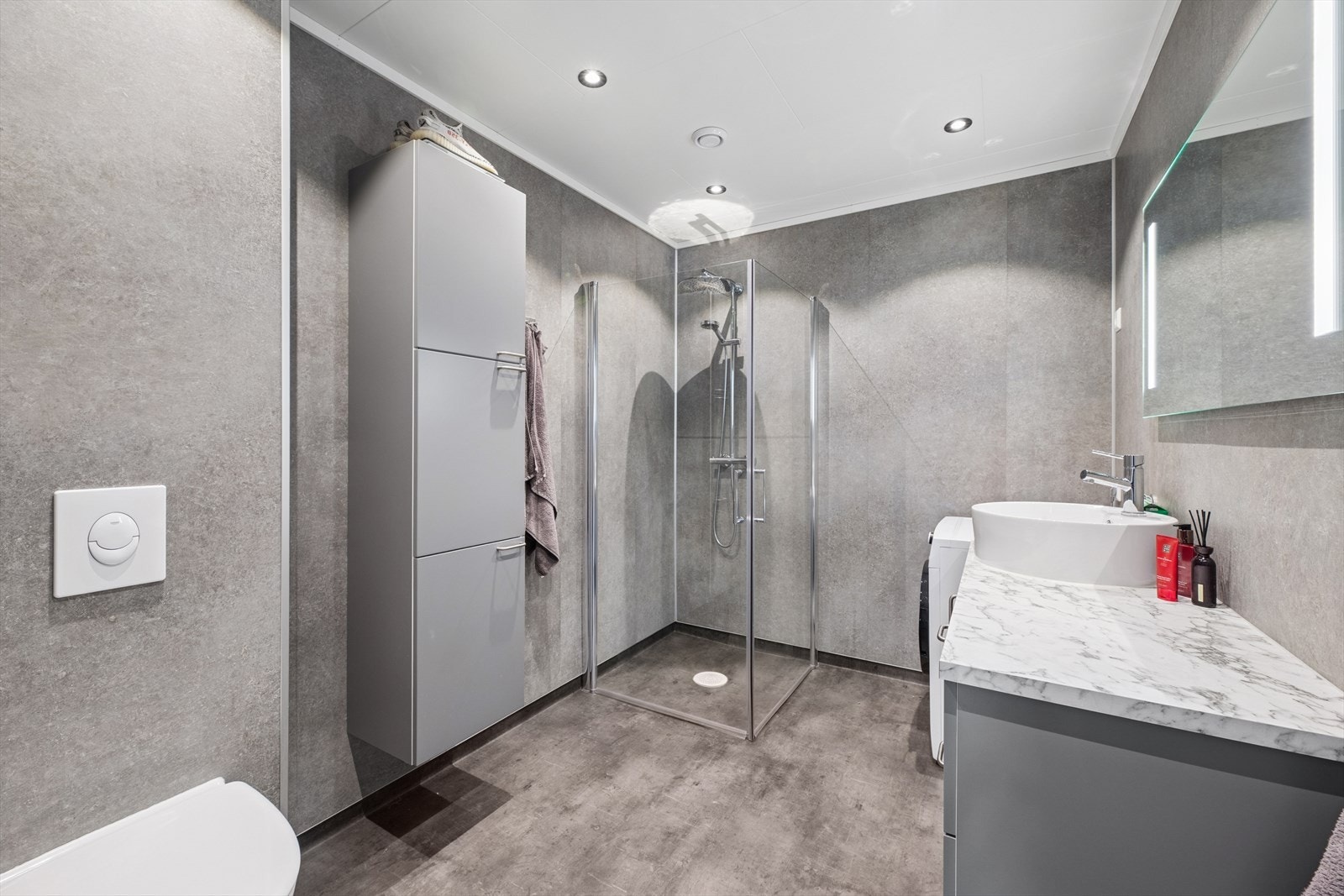 Bad i leilighet med veggmontert toalett og dusjhjørne med tropisk dusj, skaper en spa-lignende opplevelse. Galleribilde