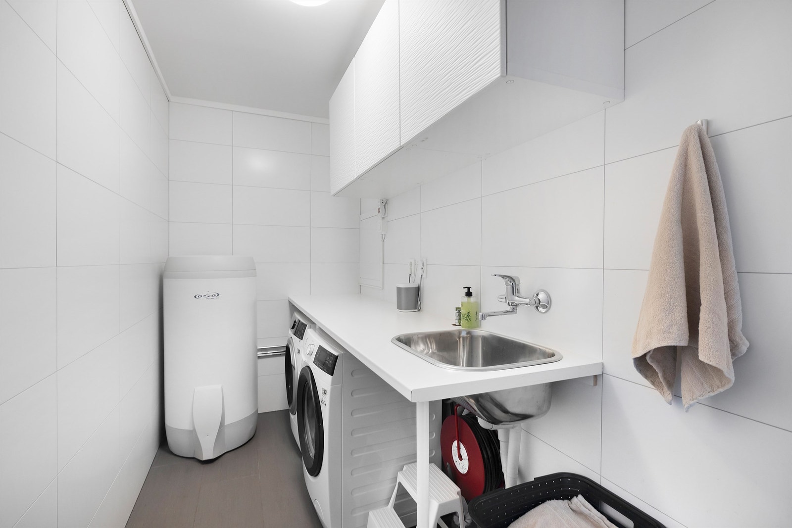 Vaskerommet er innredet med flislagt gulv med gulvvarme og flislagte vegger. Det er opplegg for vaskemaskin og tørketrommel og sentralstøvsuger. Galleribilde