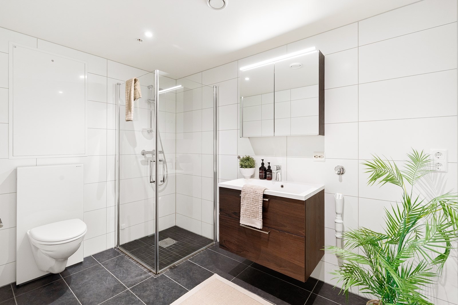 Helfliset bad med vegghengt toalett, dusjhjørne og opplegg for vaskemaskin Galleribilde