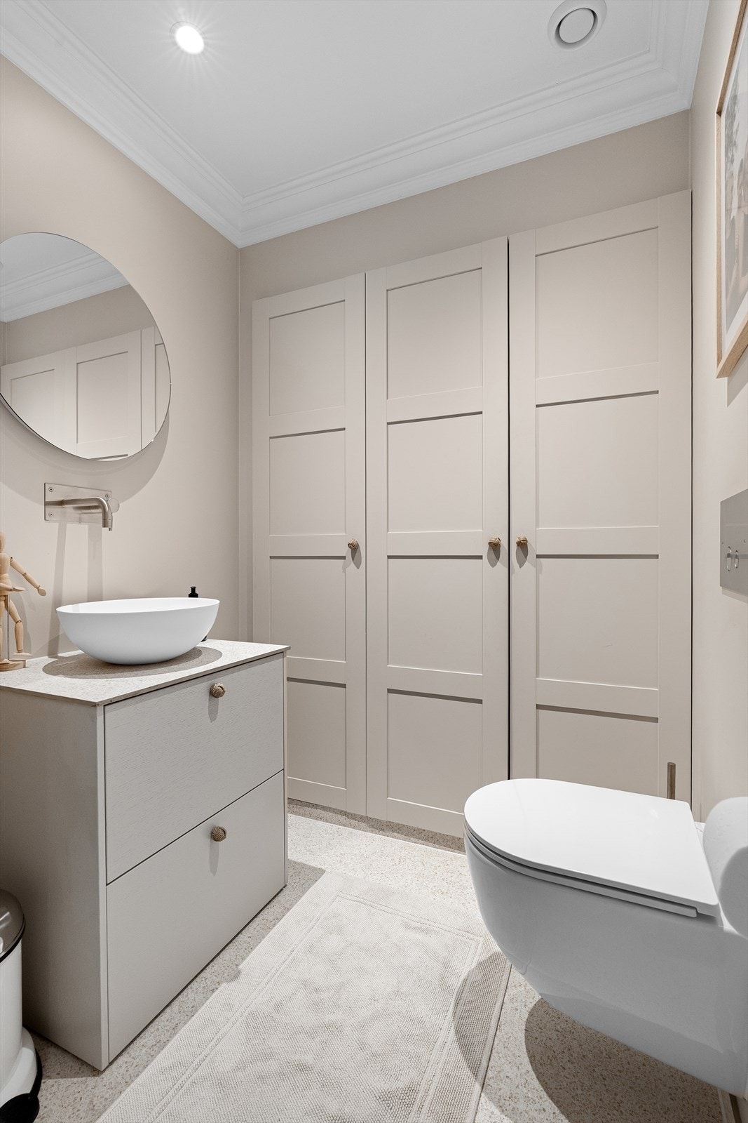 Med tilkomst fra entreen er det toalettrom med vegghengt toalett, baderomsinnredning med bollevask, vegghengt vask og speil over. Skapdørene skjuler et "hemmelig rom", hvor det er god lagringsplass under trappen. Galleribilde