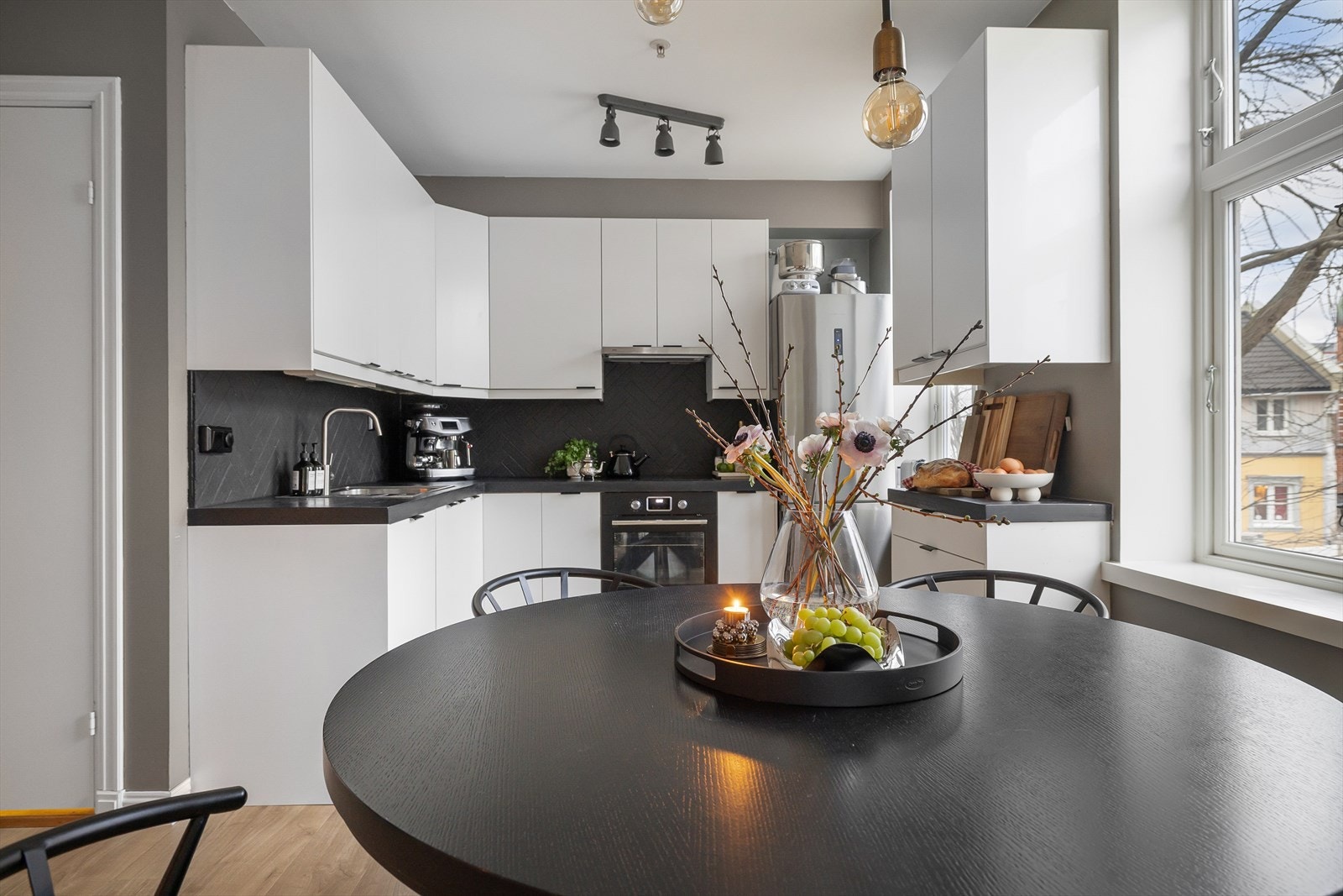 Kjøkkenet er fra IKEA og ble satt inn i 2011- med nye fronter fra Epoq i 2026. Den stilrene, hvite innredningen brer seg over to og en halv vegg og står i grafisk kontrast til den tøffe, sorte benkeplaten og bakveggens sorte fliser. Galleribilde