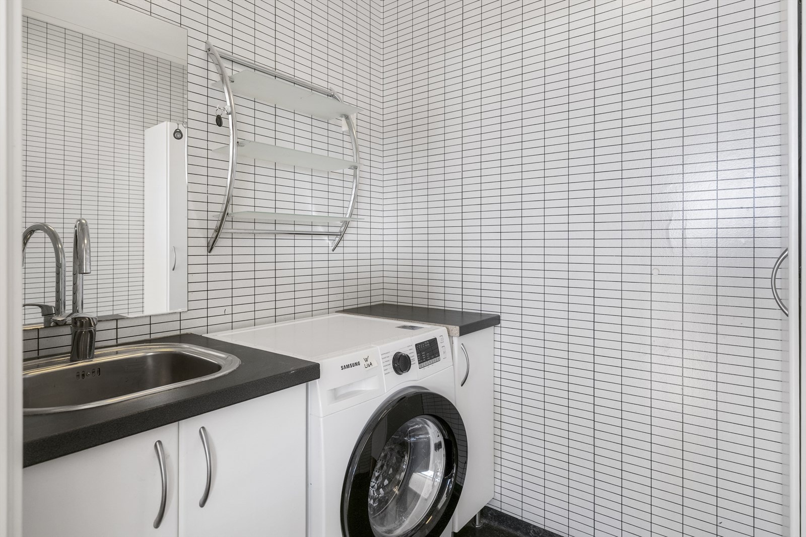 Vaskerom med samme overflater som bad, med opplegg for vaskemaskin og utslagsvask. Galleribilde