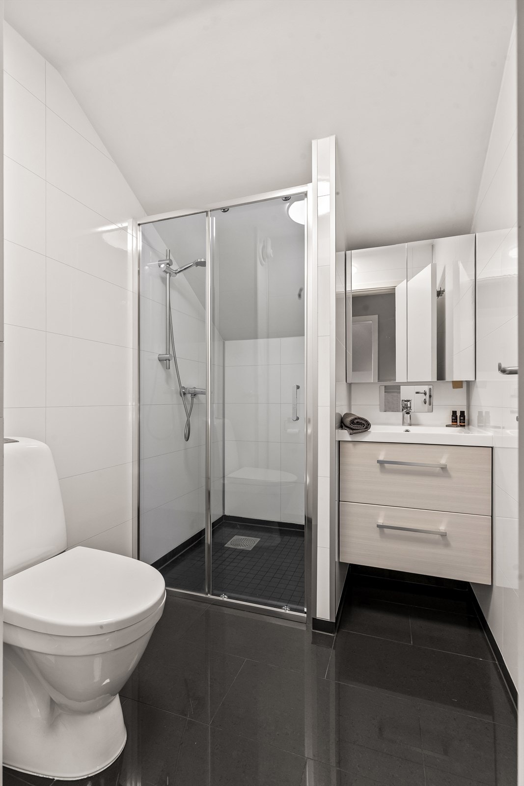 Badet har flislagt gulv, våtromsplater på veggene og en praktisk dusjnisje. Galleribilde