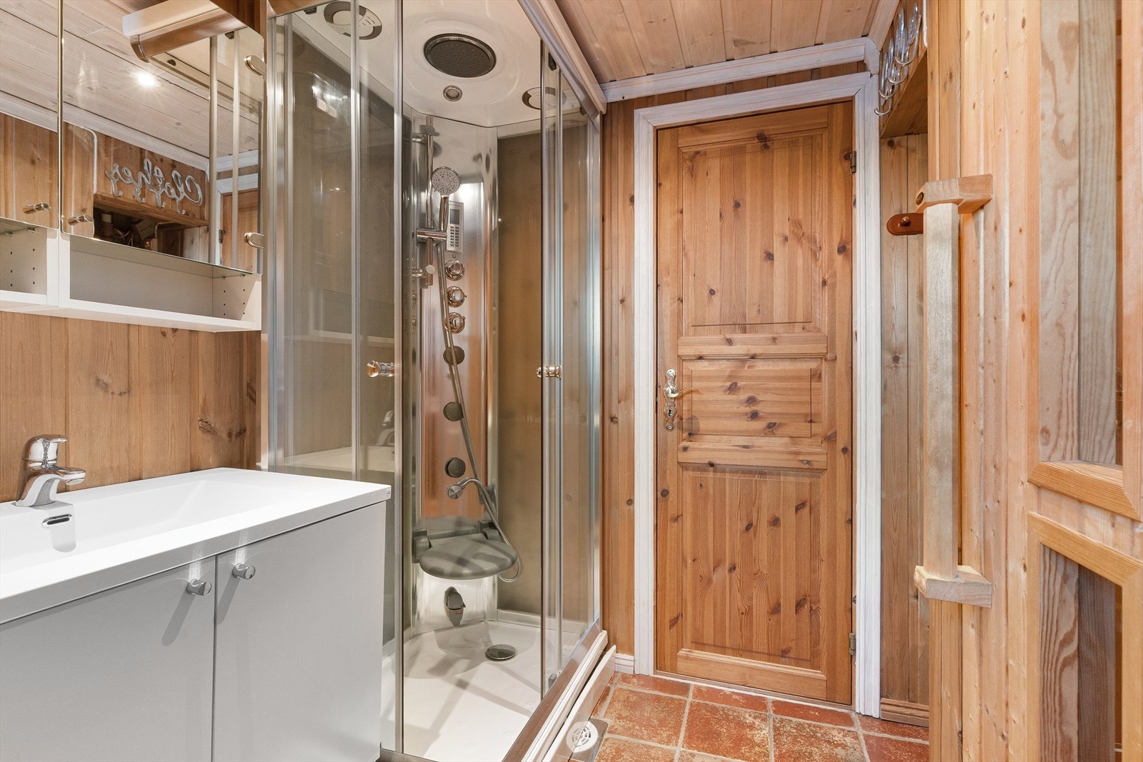 Baderommet er utstyrt med eget dusjkabinett, flislagt gulv med sluk, servant og speilskap. Galleribilde