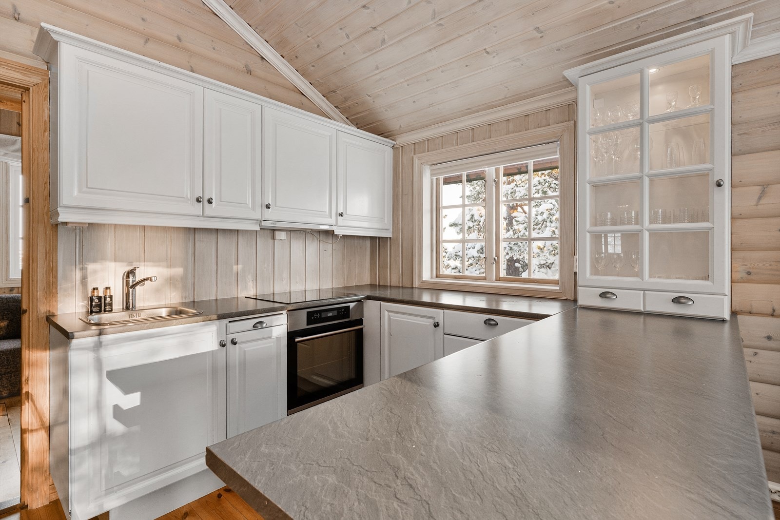 Innredningen er av heltre, og benkeplaten er laminat. Vitrineskapet har ekstra belysning innvendig. Nedfelt platetopp og integrerte stekeovn. Galleribilde